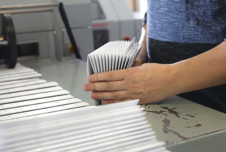 Work in the printing house. The employee packs the printed materials.